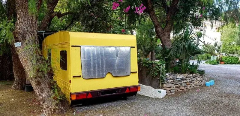 Caravana vintage amarilla entre los árboles del camping