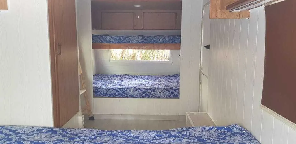 Literas y cama con ropa azul en el interior de una caravana vintage