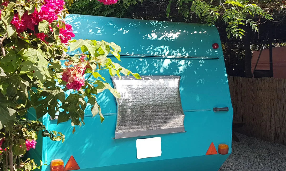 Caravane turquoise au milieu de bougainvilliers roses