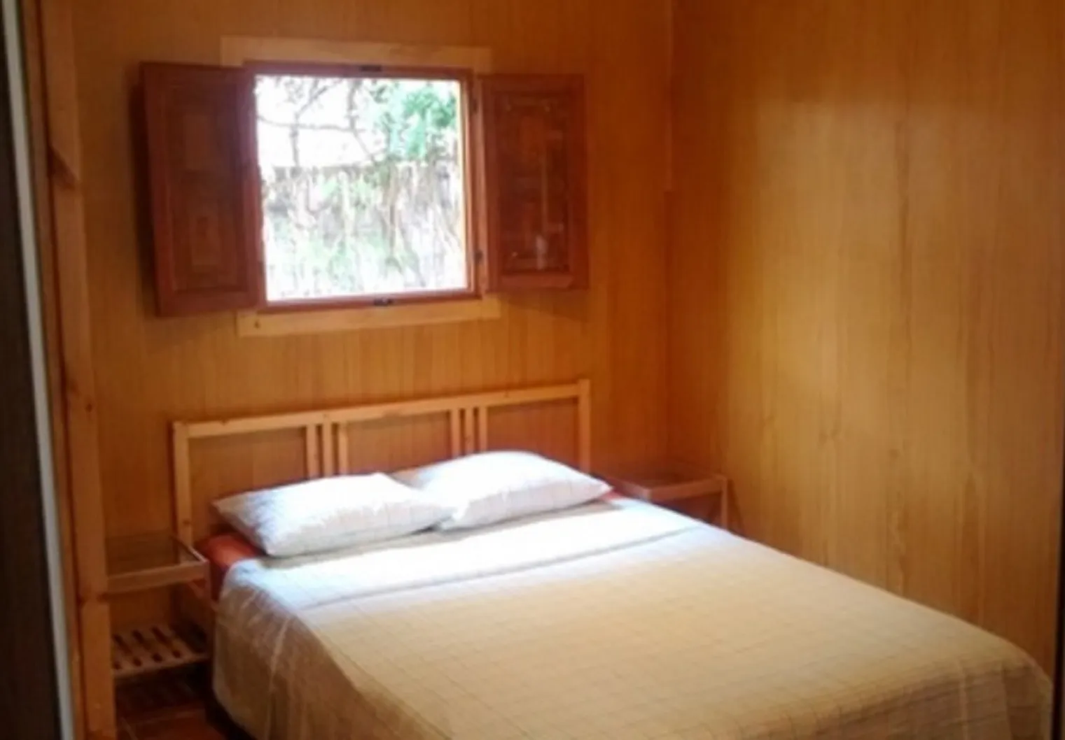 Camera della casetta in legno con letto matrimoniale e finestra sul giardino