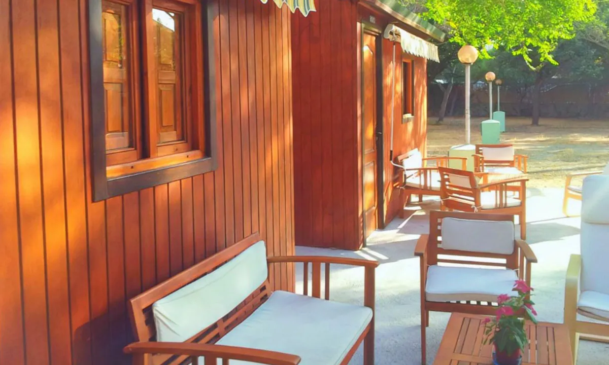 Terrasse du chalet en bois avec table et chaises à l'ombre