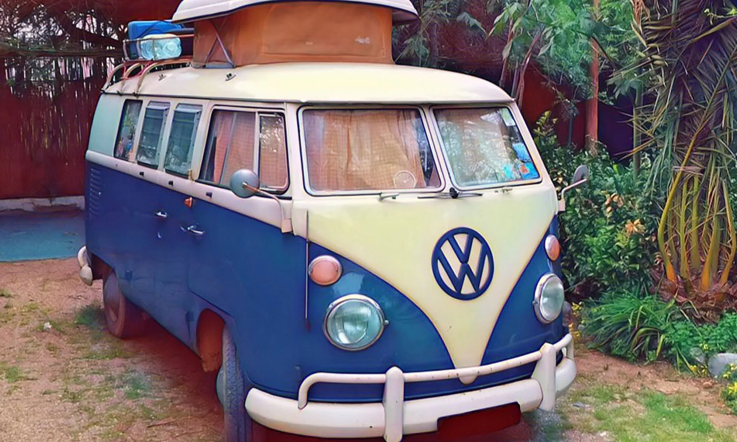 Combi Volkswagen classique bleu et blanc garé sous les arbres du camping